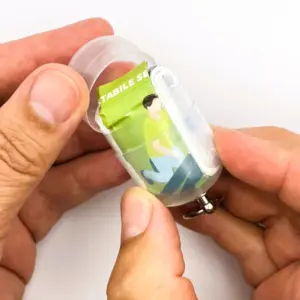 Notfall-Set für unterwegs als RettEi Logo transparent via Erste-Hilfe Schlüsselanhänger mit Beatmungstuch zur Mund zu Mund Beatmung mit transparent Kapsel teilweise geöffnet