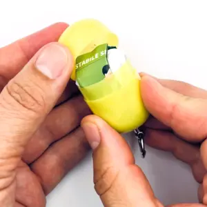 Notfall-Set für unterwegs als RettEi Logo via Erste-Hilfe Schlüsselanhänger mit Beatmungstuch zur Mund zu Mund Beatmung mit gelb Kapsel teilweise geöffnet