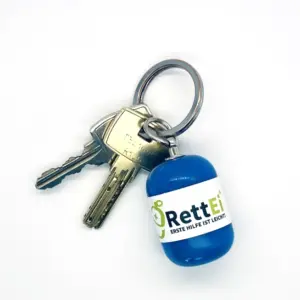 Notfall-Set-fuer-unterwegs-als-RettEi-Original-via-Erste-Hilfe-Schluesselanhaenger-mit-Beatmungstuch-zur-Mund-zu-Mund-Beatmung-mit-blauer-Kapsel-am-Schluesselbund.