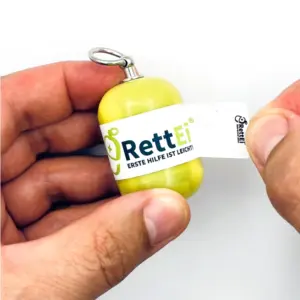 Notfall-Set-fuer-unterwegs-als-RettEi-Original-via-Erste-Hilfe-Schluesselanhaenger-mit-Beatmungstuch-zur-Mund-zu-Mund-Beatmung-mit-gelb-Kapsel-beim-oeffne