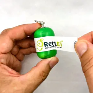 Notfall-Set-fuer-unterwegs-als-RettEi-Original-via-Erste-Hilfe-Schluesselanhaenger-mit-Beatmungstuch-zur-Mund-zu-Mund-Beatmung-mit-gruener-Kapsel-beim-oeffnen