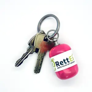 Notfall-Set-fuer-unterwegs-als-RettEi-Original-via-Erste-Hilfe-Schluesselanhaenger-mit-Beatmungstuch-zur-Mund-zu-Mund-Beatmung-mit-rosa-Kapsel-am-Schluesselbund.