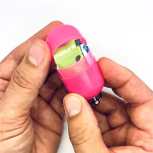 Notfall-Set-fuer-unterwegs-als-RettEi-Original-via-Erste-Hilfe-Schluesselanhaenger-mit-Beatmungstuch-zur-Mund-zu-Mund-Beatmung-mit-rosa-Kapsel-teilweise-geoeffnet.