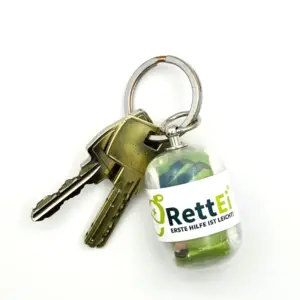 Notfall-Set-fuer-unterwegs-als-RettEi-Original-via-Erste-Hilfe-Schluesselanhaenger-mit-Beatmungstuch-zur-Mund-zu-Mund-Beatmung-mit-transparent-Kapsel-am-Schluesselbund.