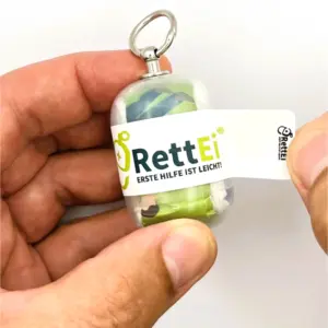 Notfall-Set-fuer-unterwegs-als-RettEi-Original-via-Erste-Hilfe-Schluesselanhaenger-mit-Beatmungstuch-zur-Mund-zu-Mund-Beatmung-mit-transparent-Kapsel-beim-oeffnen.