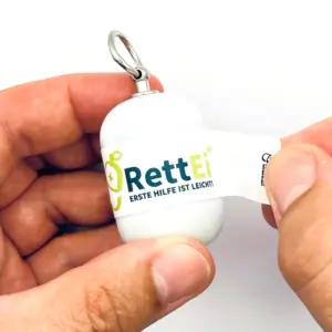 Notfall-Set-fuer-unterwegs-als-RettEi-Original-via-Erste-Hilfe-Schluesselanhaenger-mit-Beatmungstuch-zur-Mund-zu-Mund-Beatmung-mit-weiss-Kapsel-beim-oeffnen